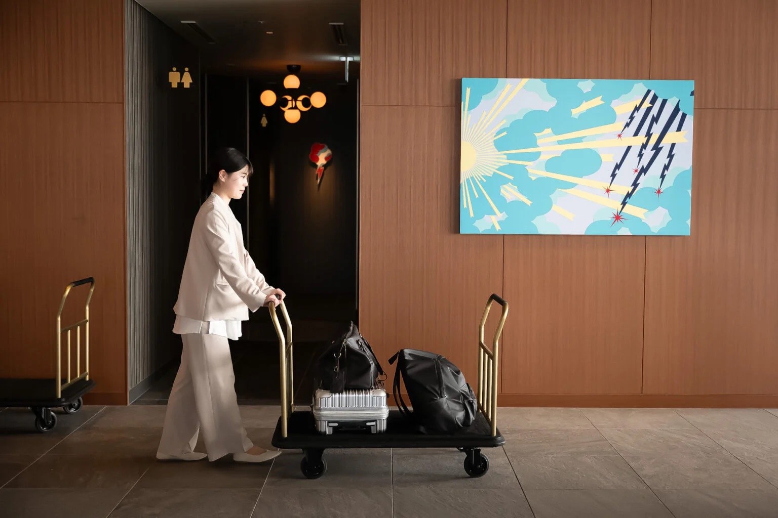 ベージュの制服を着用したホテルスタッフが荷物を運んでいる様子