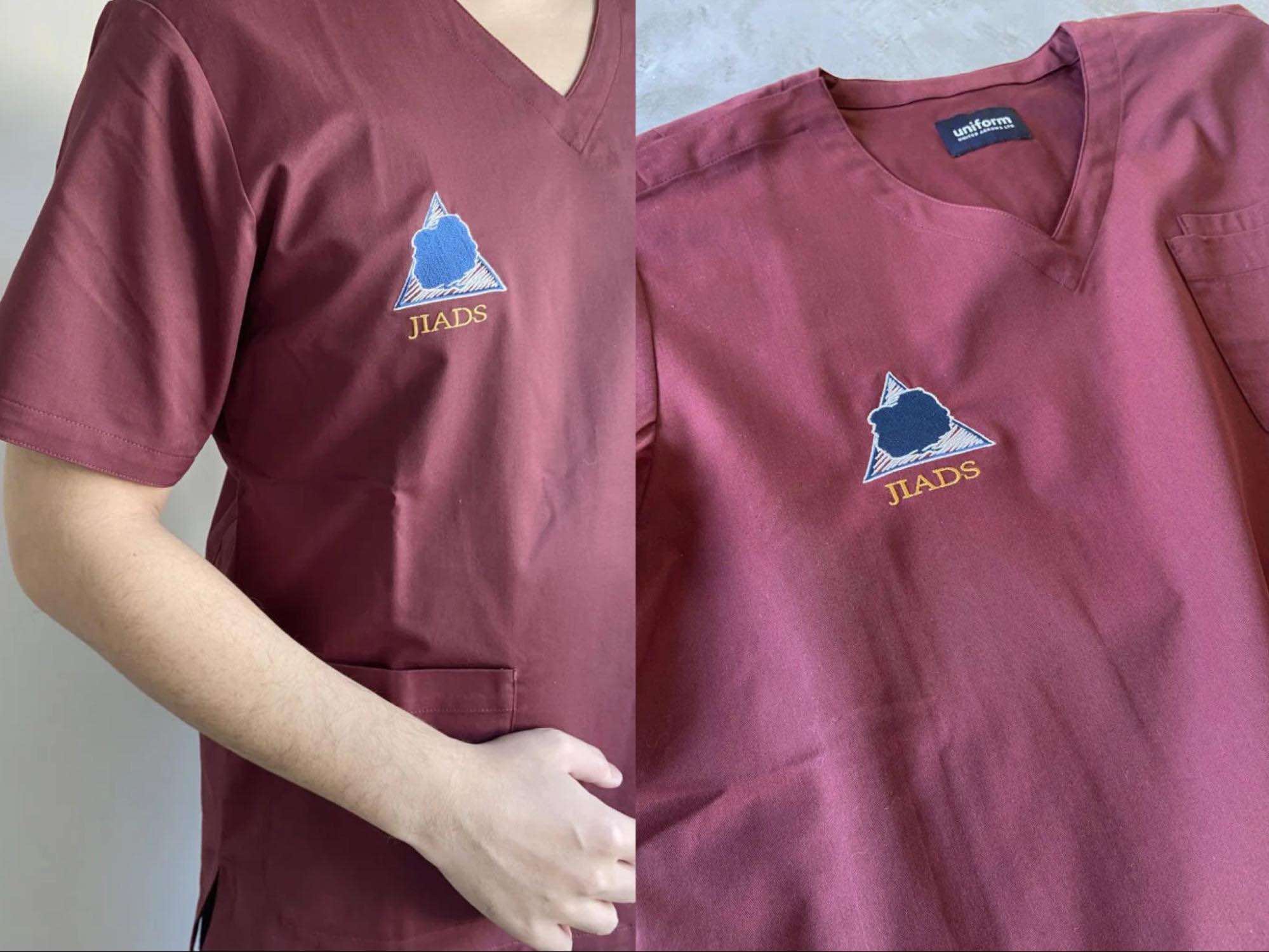 胸元に刺繍のロゴが入ったボルドーのスクラブ