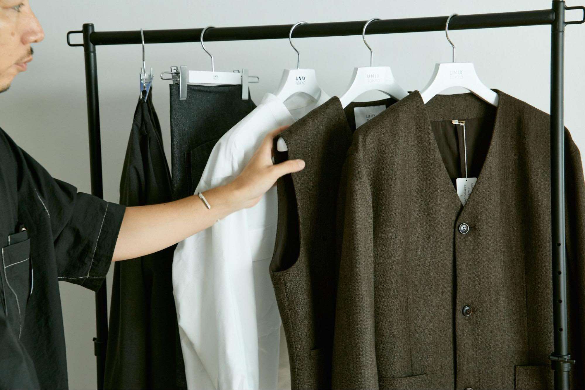 ハンガーラックにかかった制服に触れているスタッフ