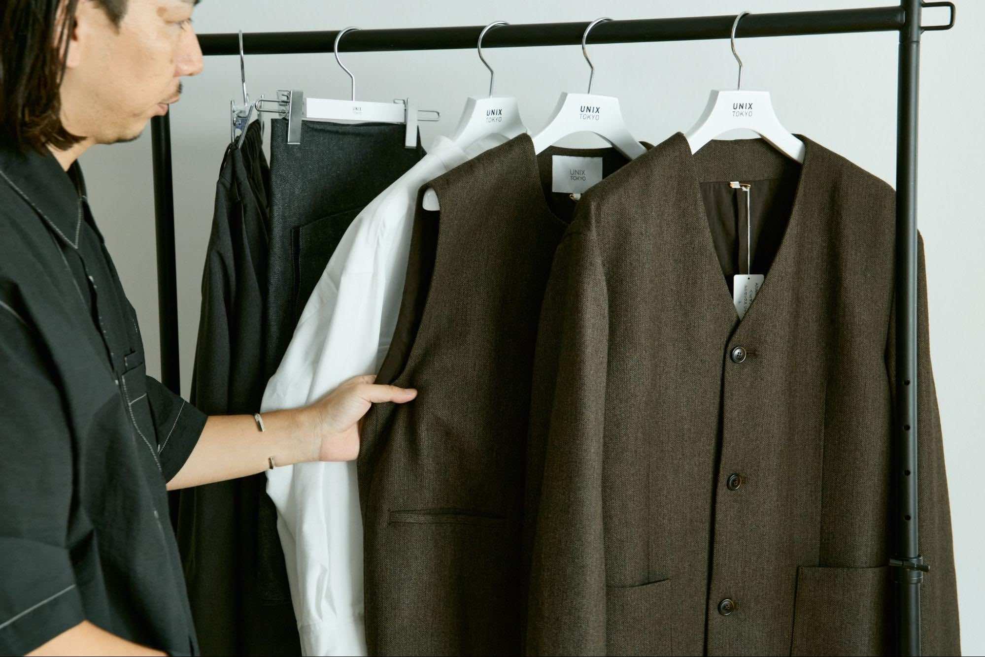 スタッフがハンガーにかかっている服に触れている様子