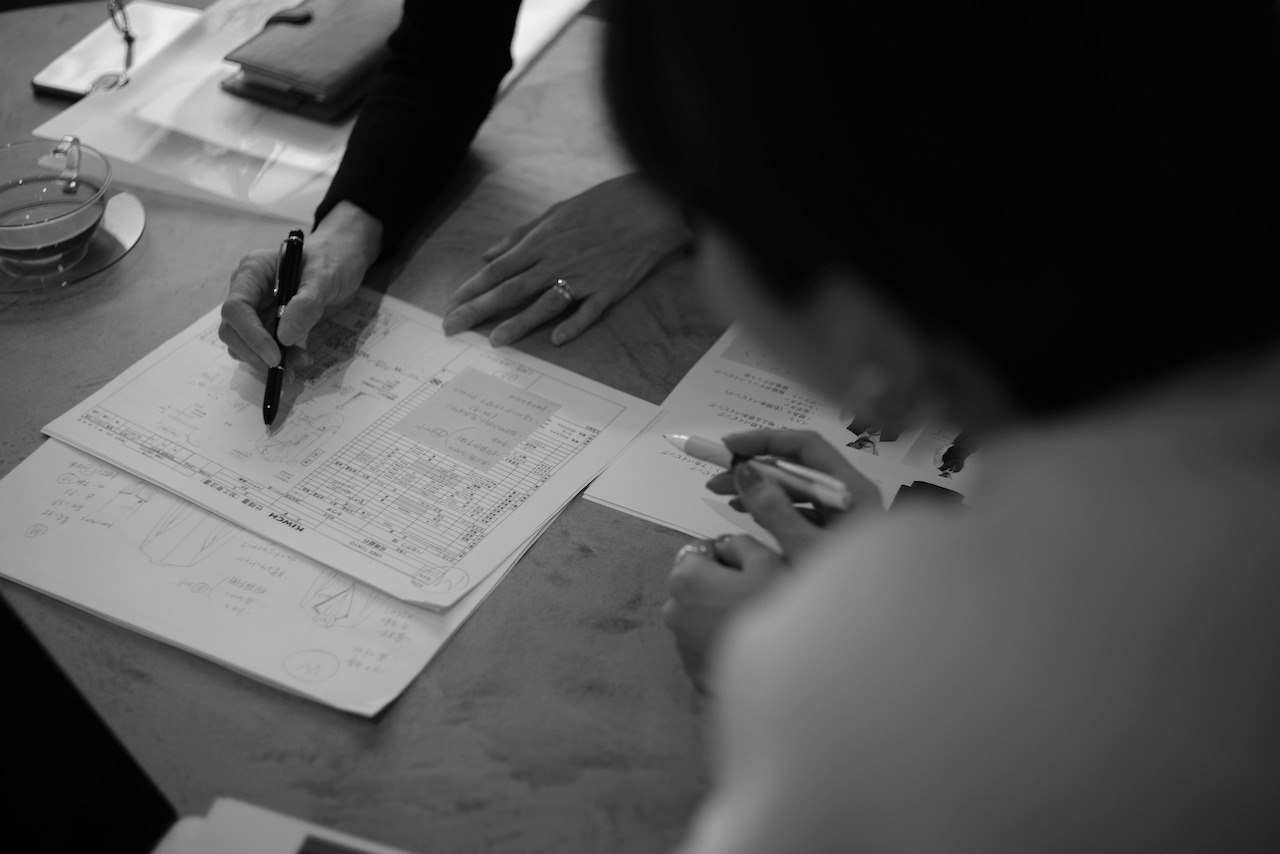 書類にメモしながら打ち合わせをしている様子のモノクロ写真