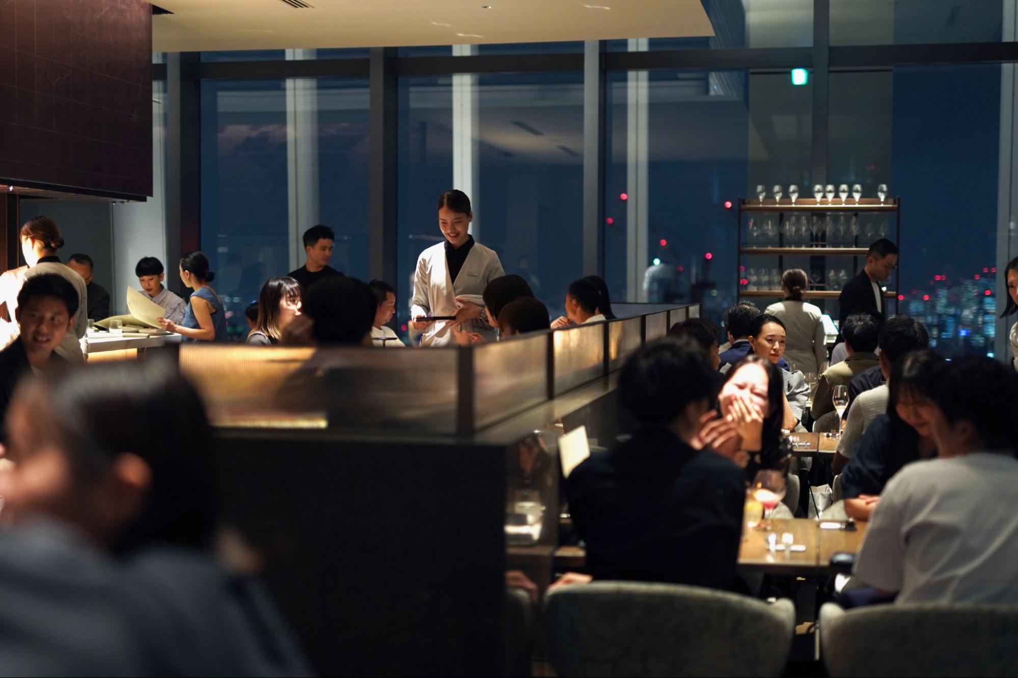 レストランのディナータイムに笑顔で接客する女性スタッフの様子