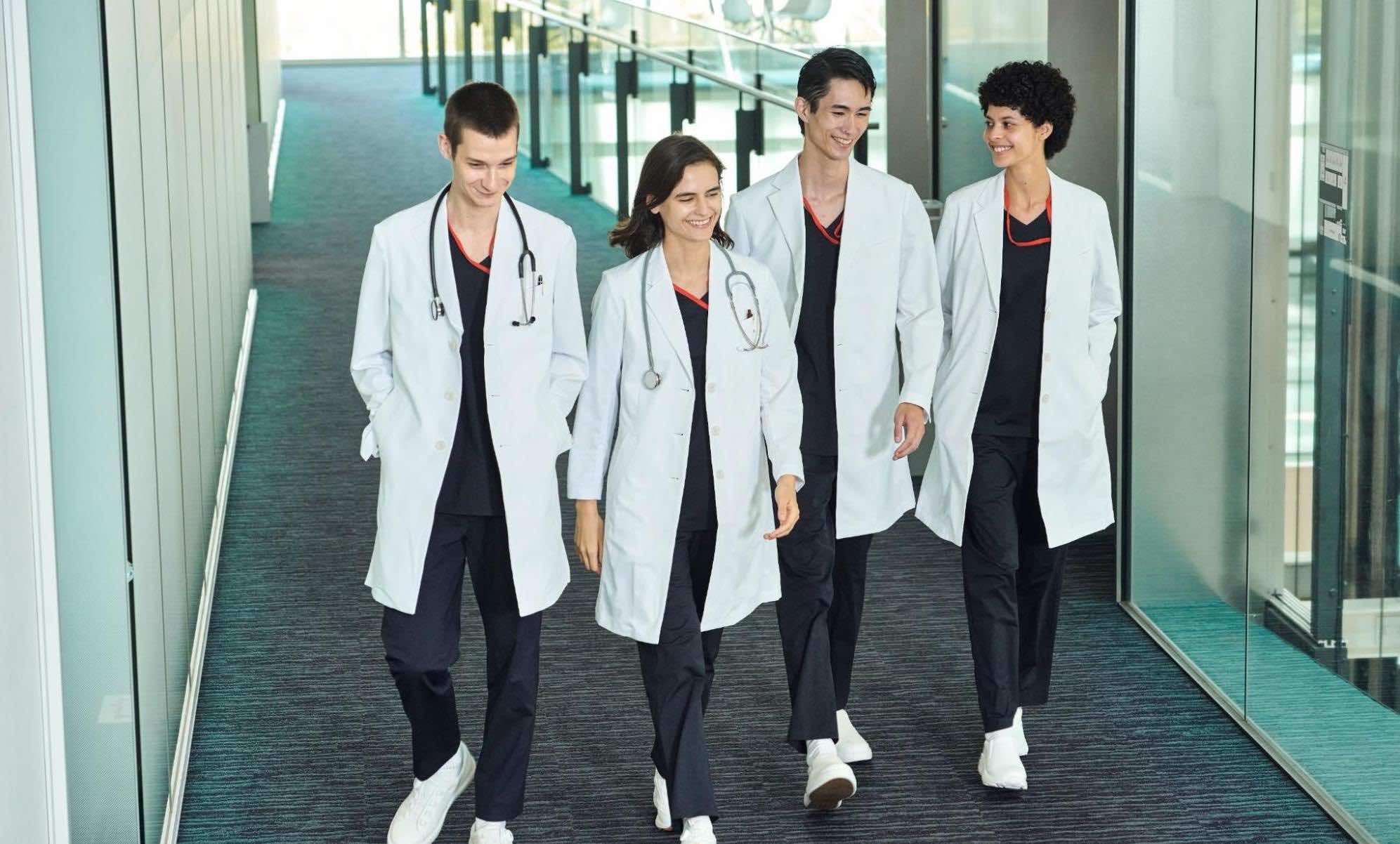 白衣を羽織った医療スタッフ4名が並んで談笑している様子