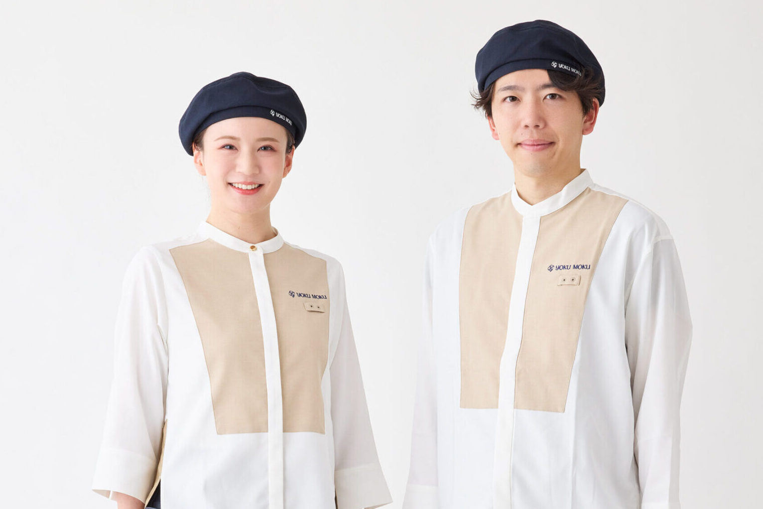 ベージュと白のユニフォーム、ネイビーの帽子を着用した洋菓子店のスタッフ