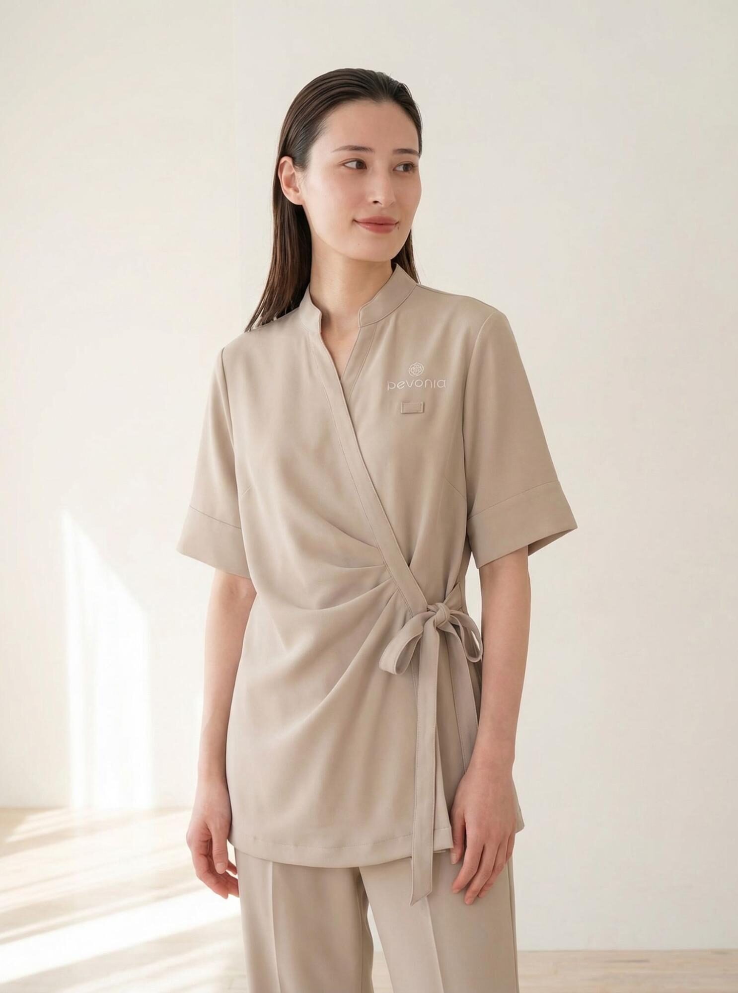 ベージュのユニフォームを着用した女性スタッフ