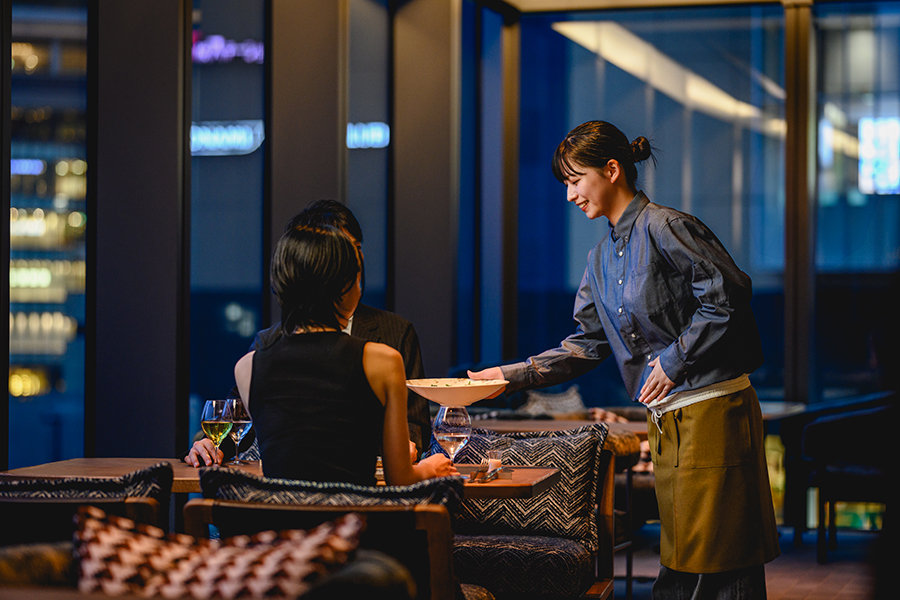 ネイビーの制服を着用したレストランスタッフが料理を提供している様子